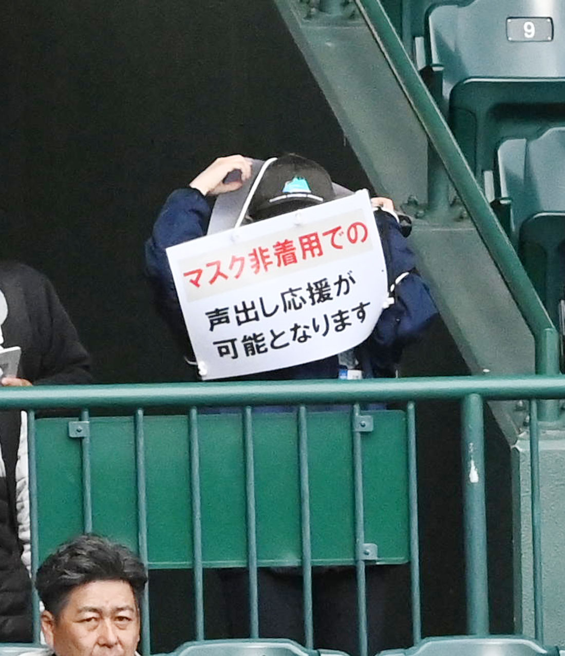 北陸対高知　「マスク非着用での声出し応援が可能となりました」と書かれたプラカードをぶらさげる球場スタッフ（撮影・前岡正明）
