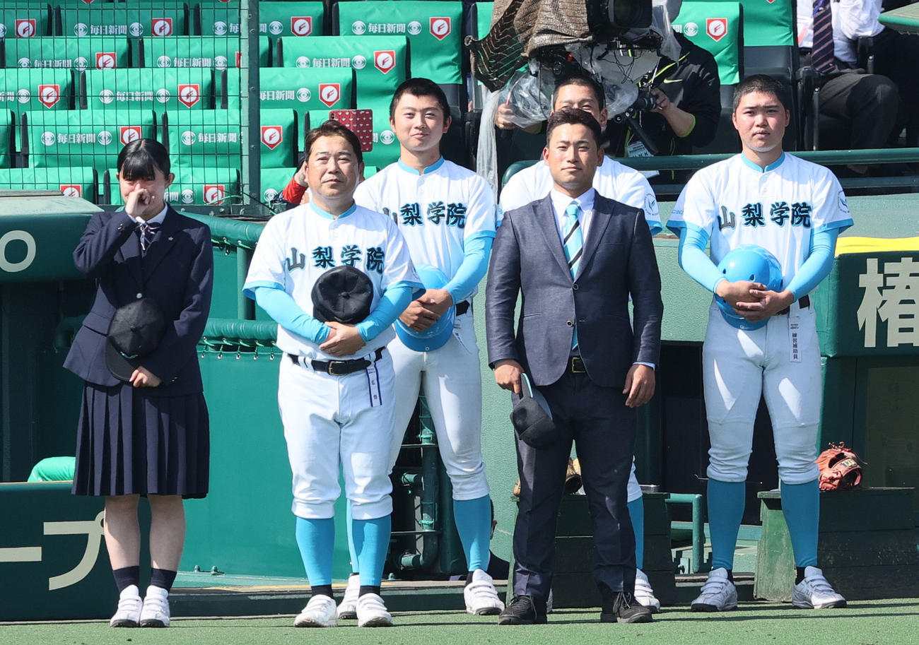 報徳学園対山梨学院　初優勝を決めた山梨学院の吉田監督（左から2人目）は校歌を聞く（撮影・上山淳一）