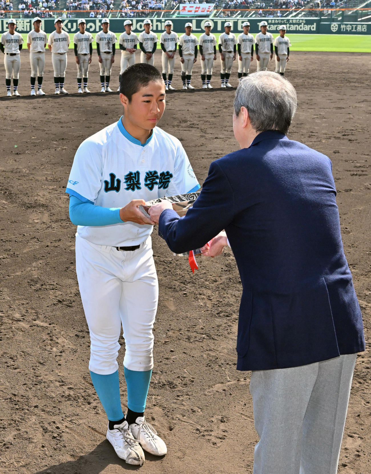 優勝杯を受け取る山梨学院の林謙吾選手＝阪神甲子園球場で2023年4月1日、毎日新聞代表撮影