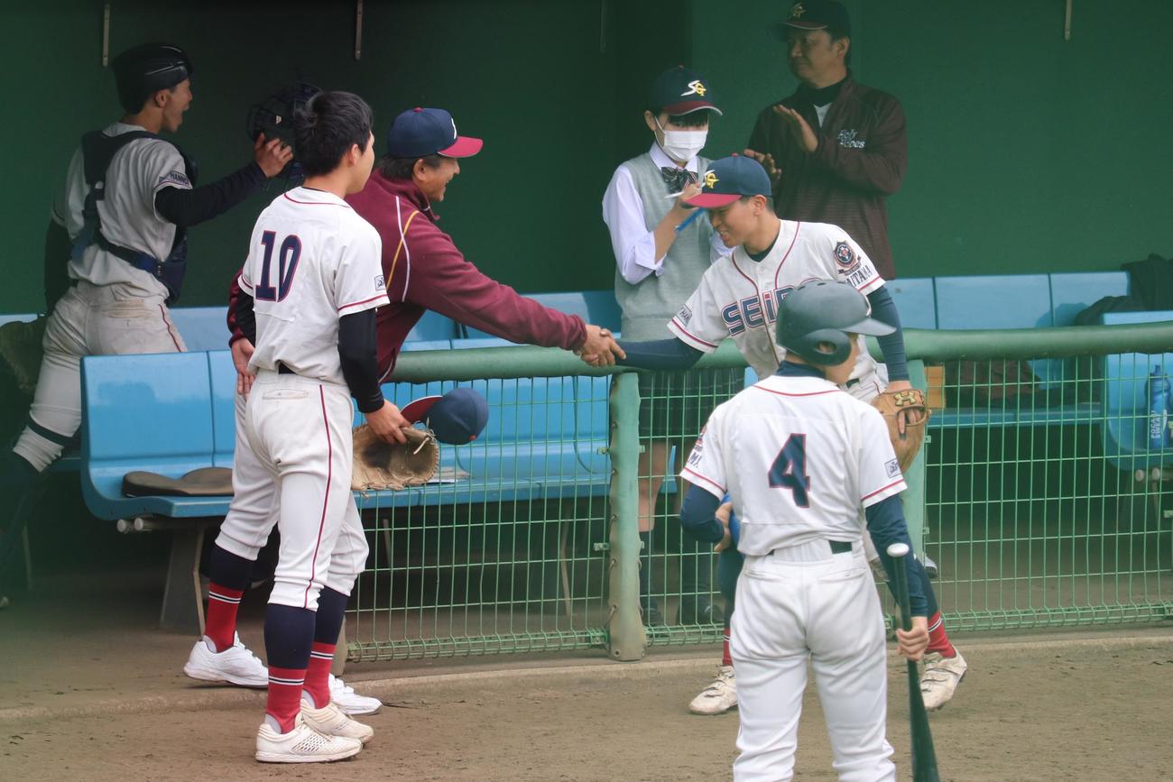 春日部東－聖望学園　好プレーの選手を握手で迎える、聖望学園の飯牟礼監督（撮影・保坂淑子）