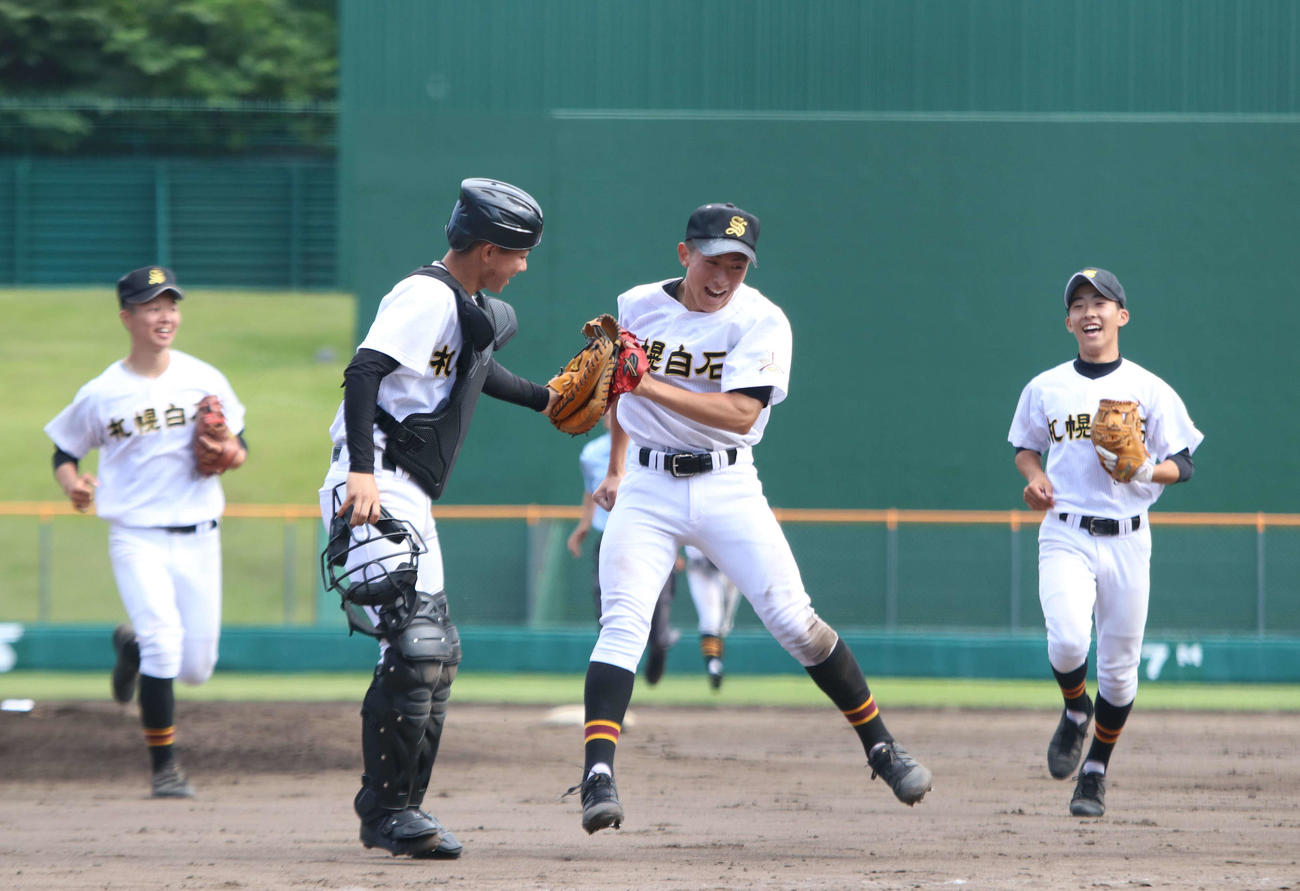 札幌白石対石狩南　9回最後の打者を打ち取りグラブでタッチを交わす札幌白石の田村（中央左）と辰己（中央右）（撮影・山崎純一）