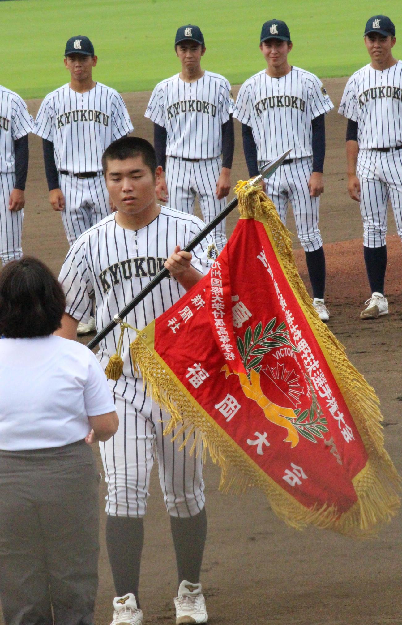 嘉穂総合対九州国際大付　試合前、優勝旗を返還する九州国際大付・佐倉〓（人ベンに峡の旧字体のツクリ）史朗主将（撮影・菊川光一）＝2023年7月7日、北九州市民球場