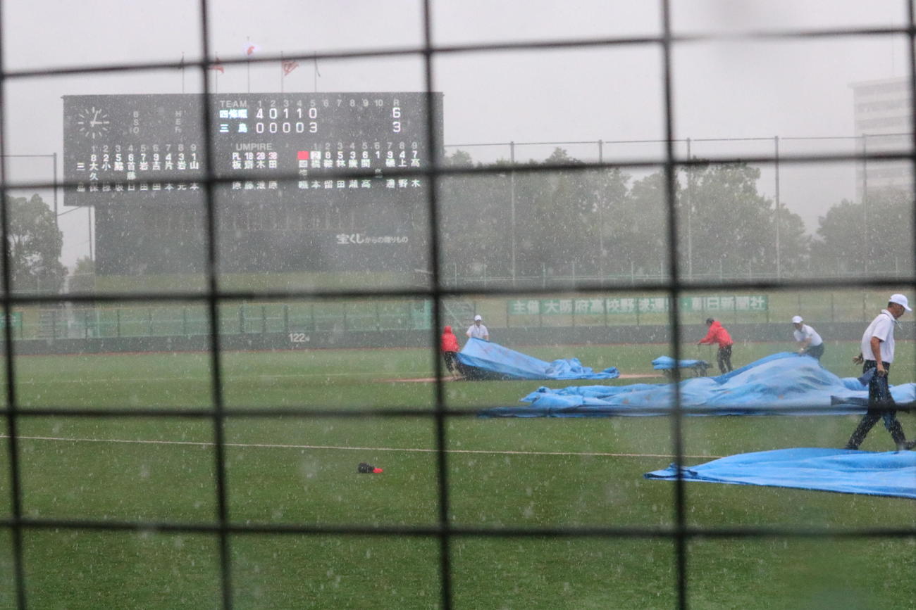 四條畷対三島　5回裏終了時に雨脚が強まり、シートをかぶせるスタッフ（撮影・林亮佑）＝2023年7月9日、南港中央