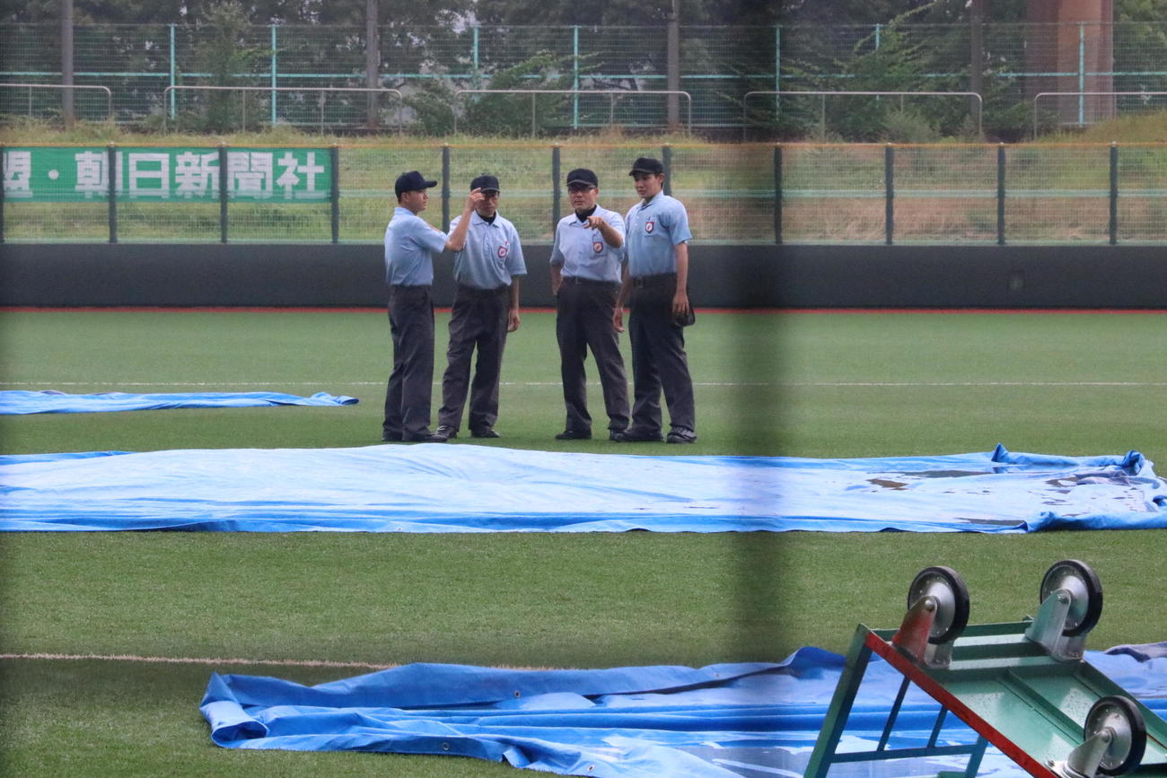 四條畷対三島　5回裏終了時に雨脚が強まり試合が中断し、審判団が協議する（撮影・林亮佑）＝2023年7月9日、南港中央