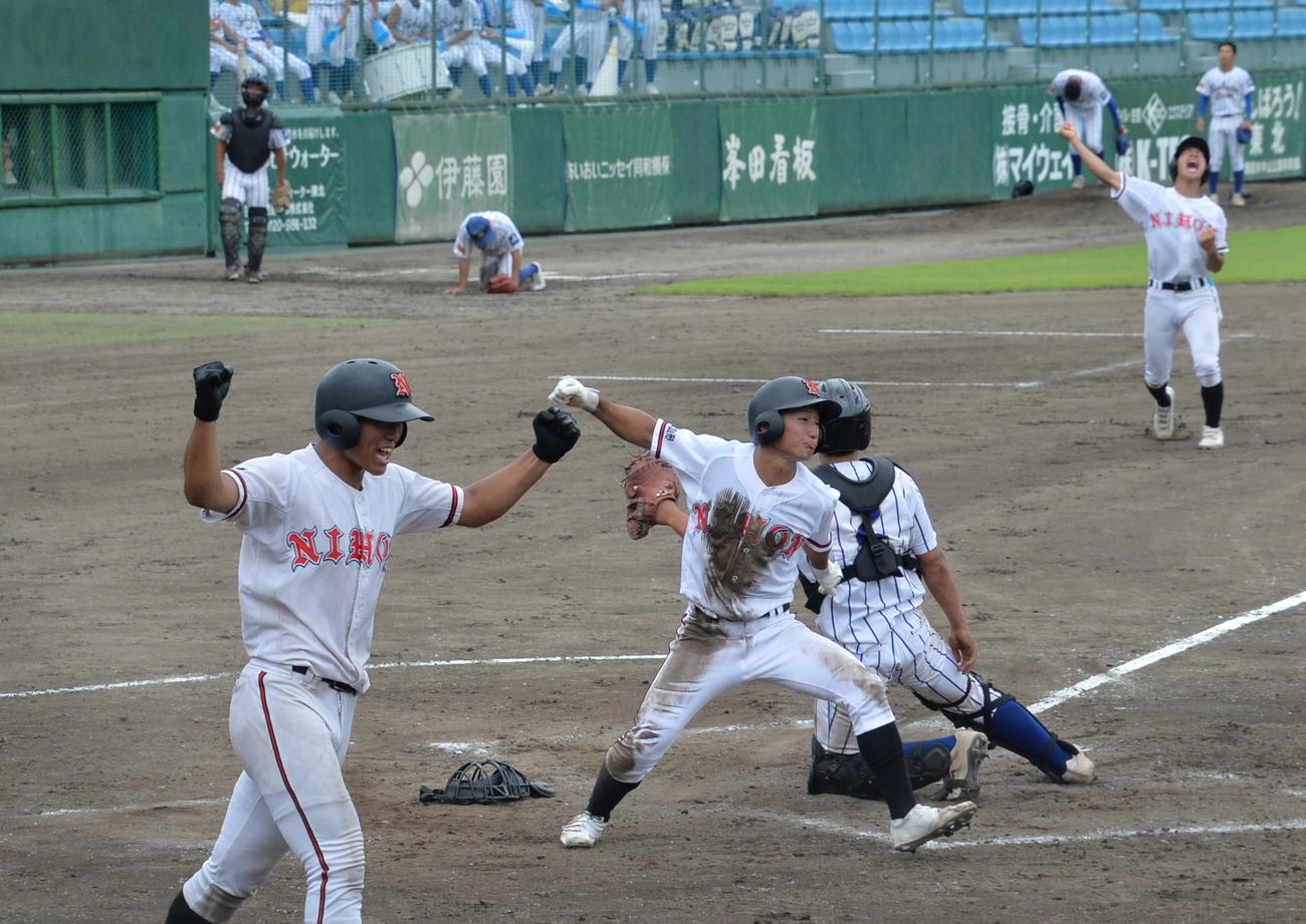 酒田南対日大山形　9回2死二塁、二塁から本塁へヘッドスライディングで生還した日大山形・土屋（中央）は右拳を振り上げ、大喜び（撮影・濱本神威）