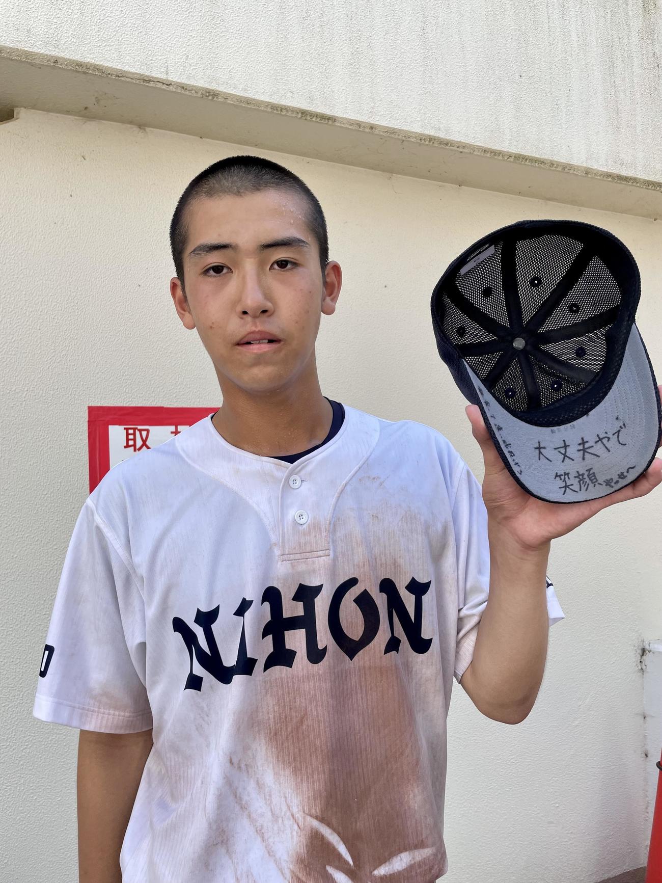 日本工大駒場対日大豊山　チームメートからのメッセージ「大丈夫やで　笑顔　飯食って速い球投げろ」が書かれた帽子のツバを披露する日大豊山・村井（撮影・保坂恭子）