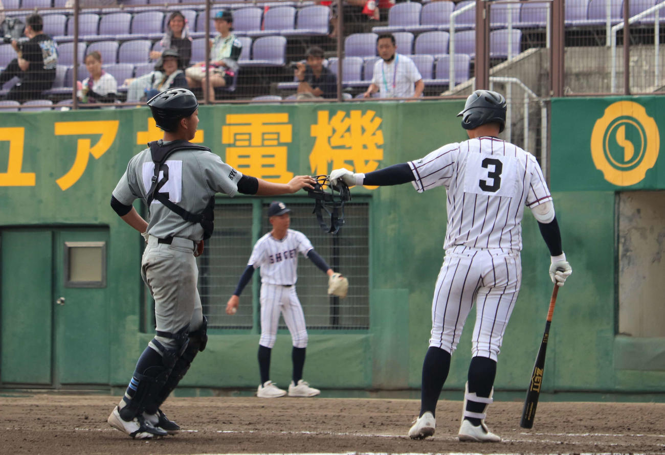 京都両洋対京都翔英　前の打者とのプレーで相手捕手が落としたマスクを拾って渡す京都翔英の小笠原蒼内野手（撮影・中島麗）