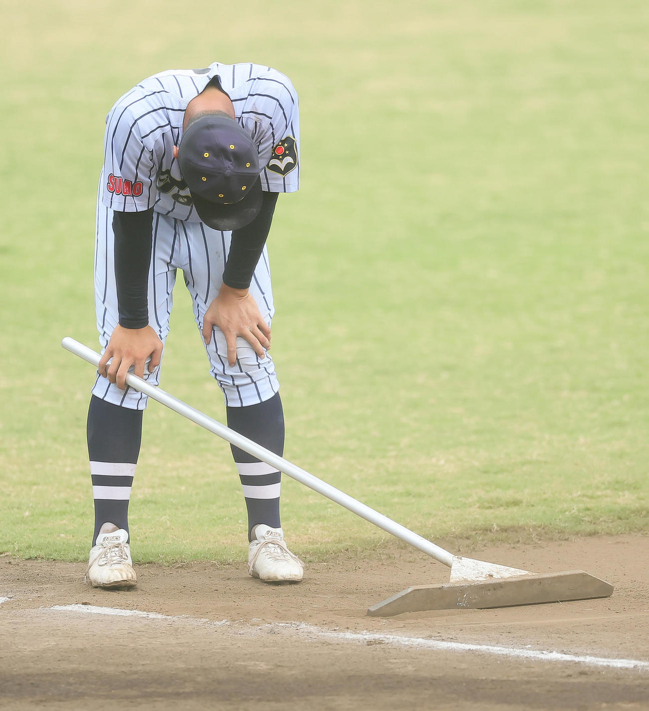 駒大高に敗れ、肩を落としながら試合後のグラウンド整備を行う東海大菅生・日当（撮影・足立雅史）