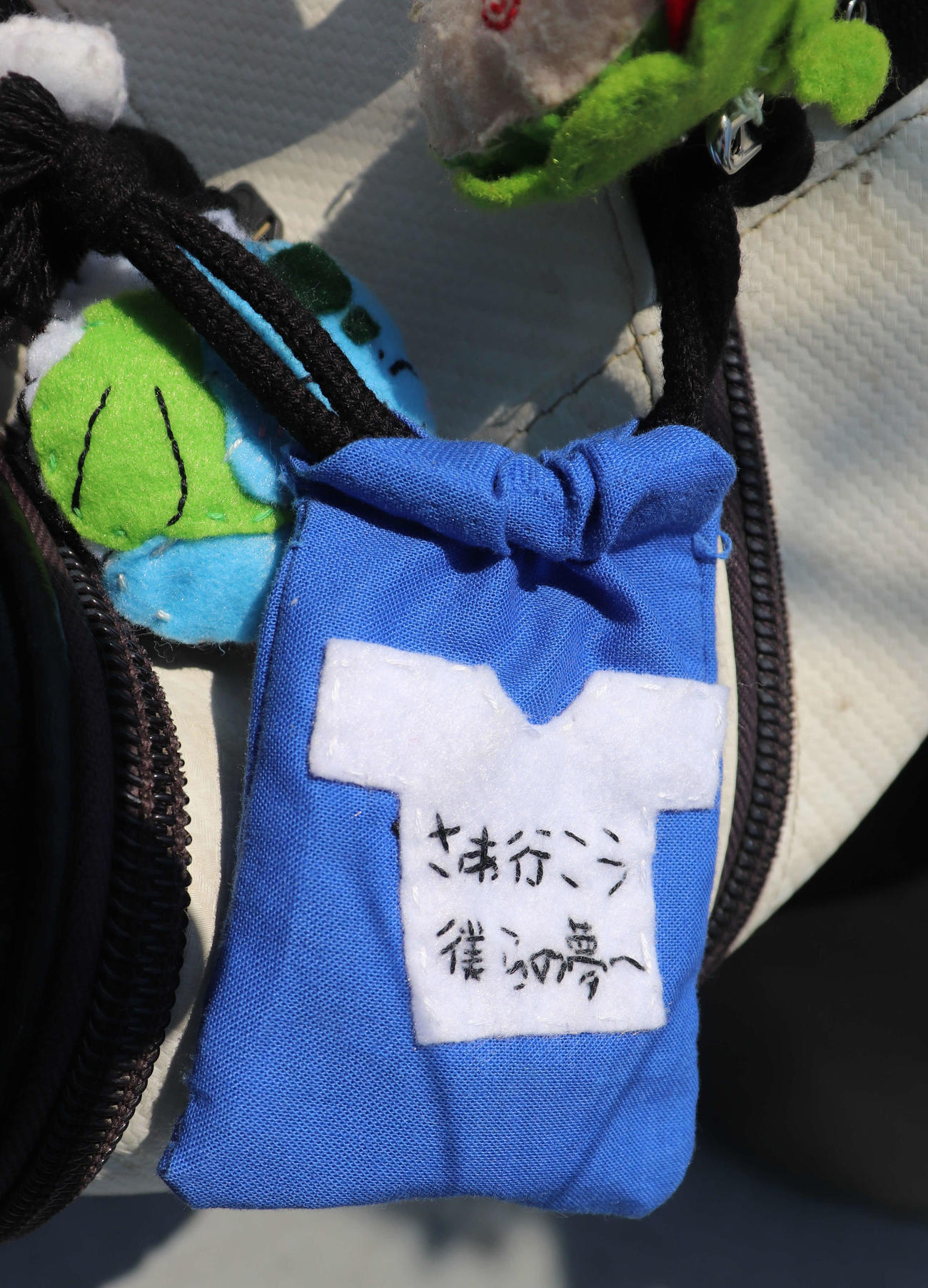 八尾の巾着型のお守り。大会スローガン「さあ行こう　僕らの夢へ」の刺しゅう入り。巾着の中にはマネジャー手書きのメッセージカードが添えられている（撮影・中島麗）
