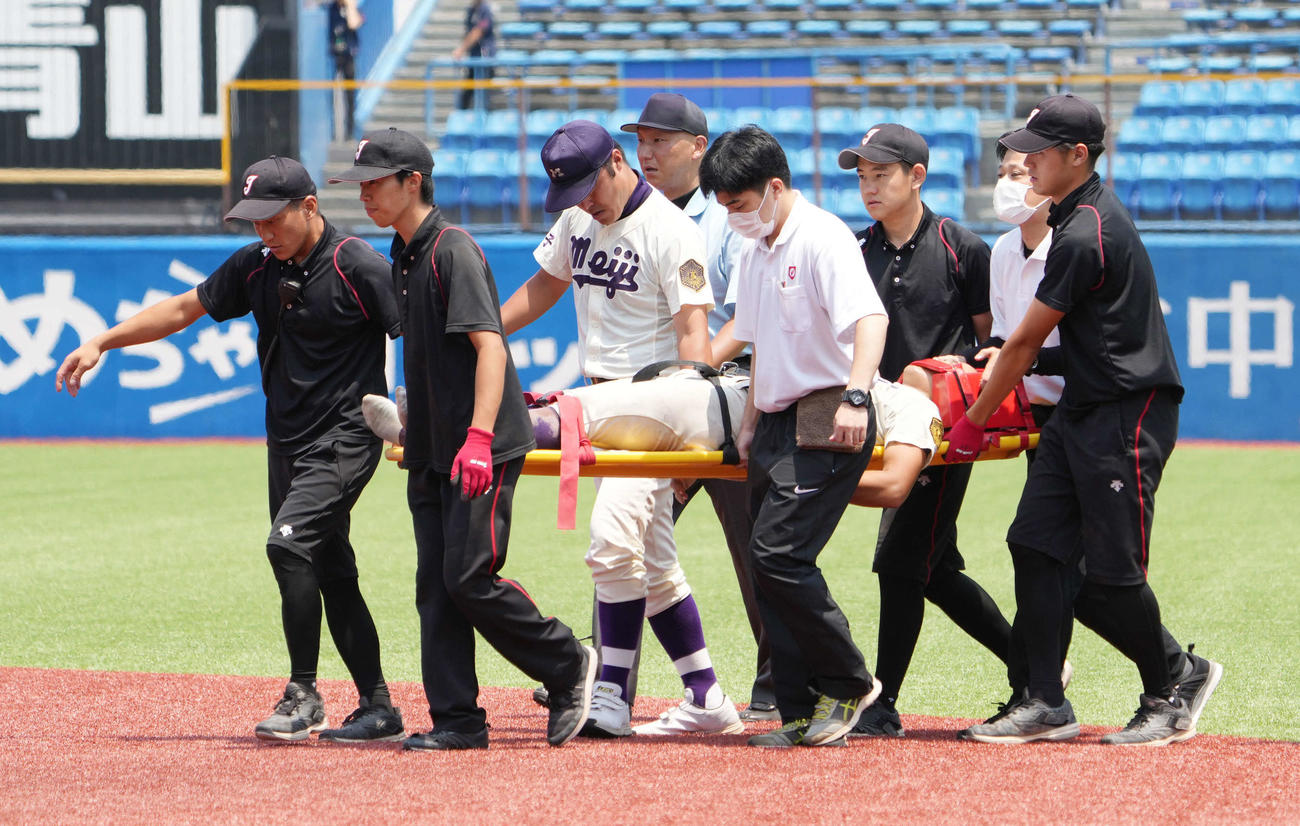 明大中野八王子対日大三　4回裏日大三2死、二宮の打球を追いフェンスに激突した明大中野八王子の西川右翼手はケガの治療のため担架で運ばれる（撮影・小沢裕）