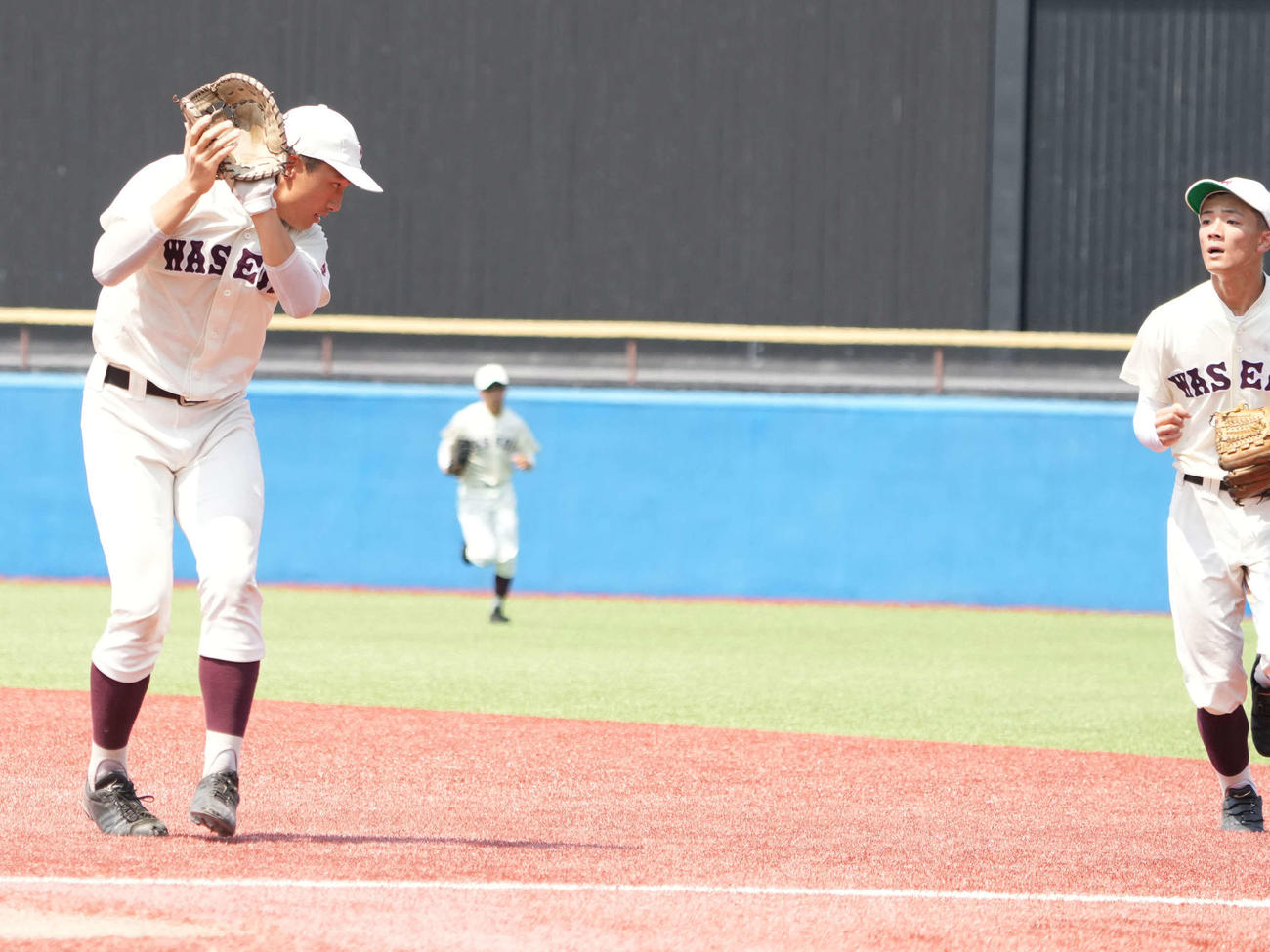 早大学院対日大鶴ヶ丘　4回裏日大鶴ヶ丘2死一塁、伊藤の飛球が太陽と重なり、顔を背ける早大学院笠尾一塁手。右端は井上二塁手（撮影・小沢裕）