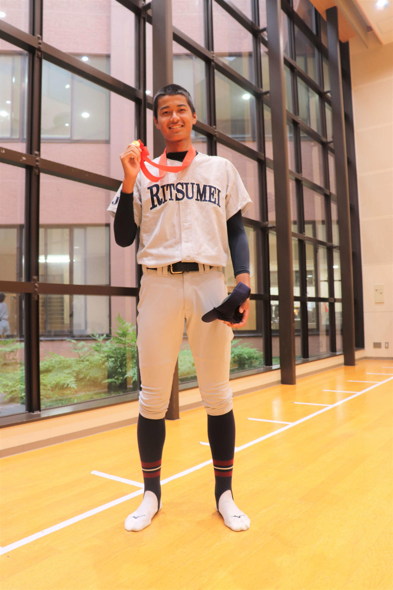 笑顔で優勝メダルを手に持つ身長196.5センチの立命館宇治のエース・十川奨己投手（2年）（撮影・中島麗）