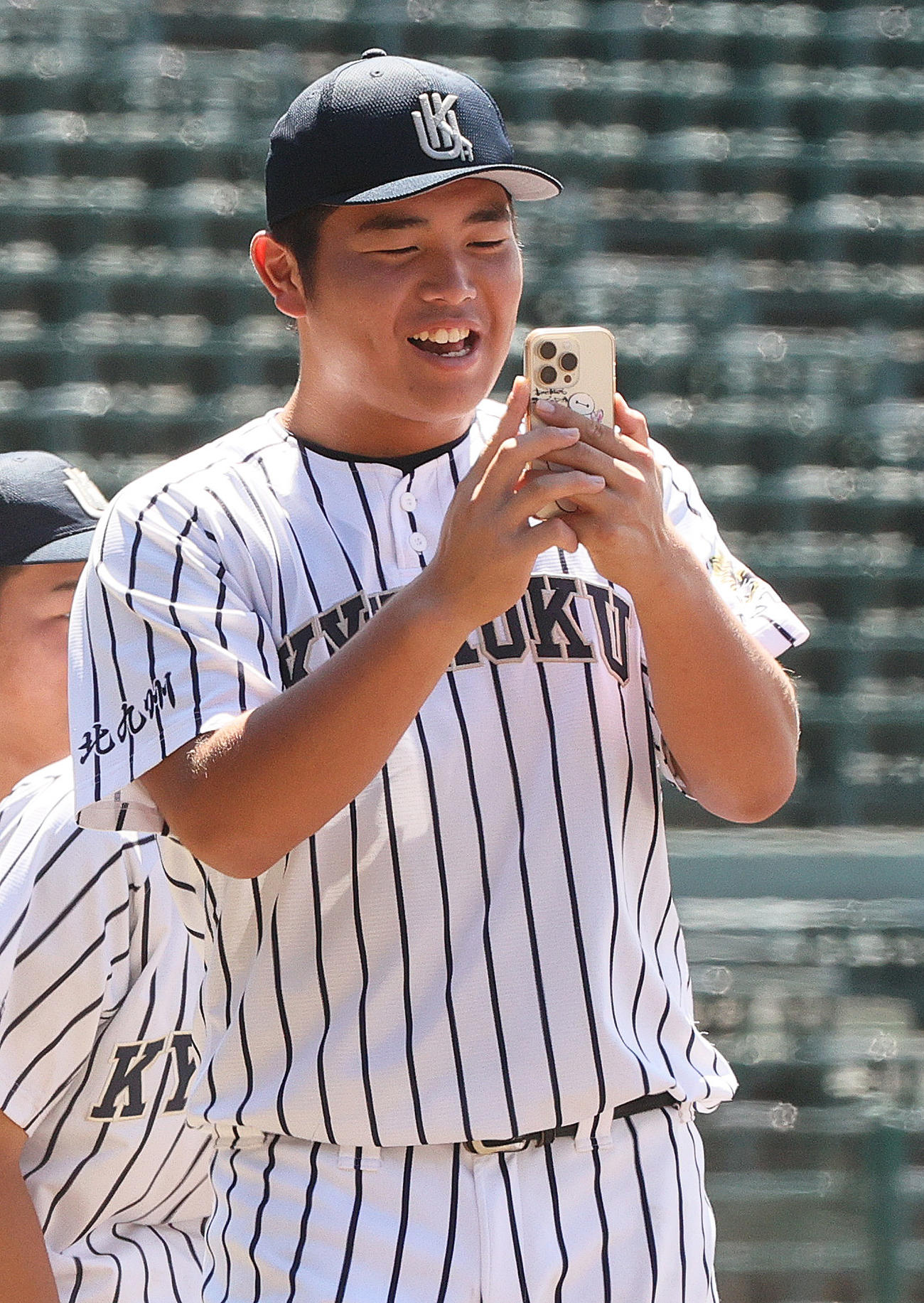 甲子園球場見学で仲間を撮影する九州国際大付の佐倉（撮影・上山淳一）