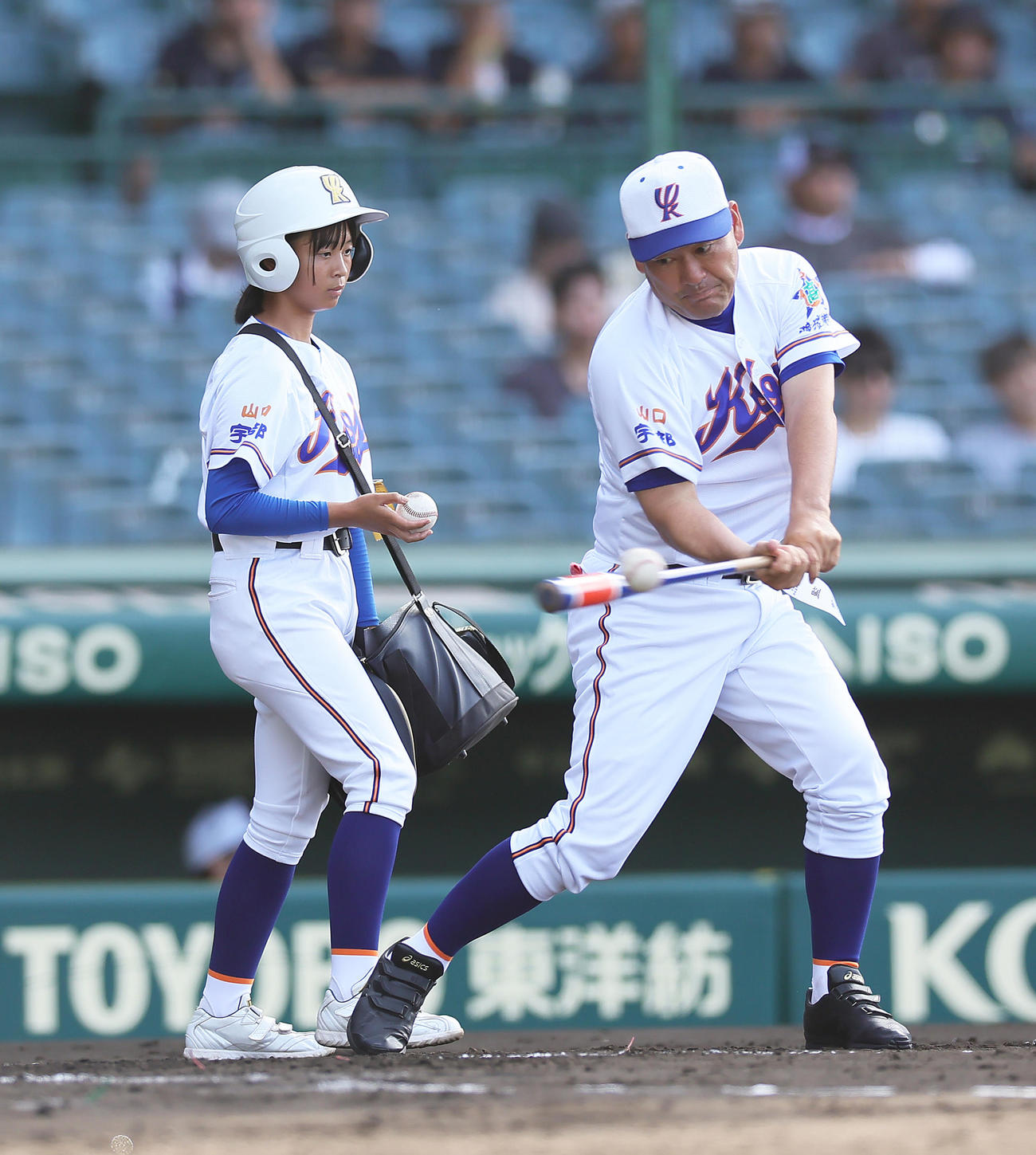 試合前、宇部鴻城・尾崎監督（右）の横でノック補助を行う岡野マネジャー（撮影・足立雅史）