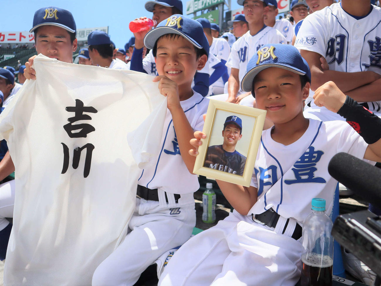 全国高校野球選手権　明豊対北海　アルプスで吉川孝成さんの練習着と遺影を手に応援する、弟の悠之輔さん（左）と寛太さん（撮影・村松万里子）