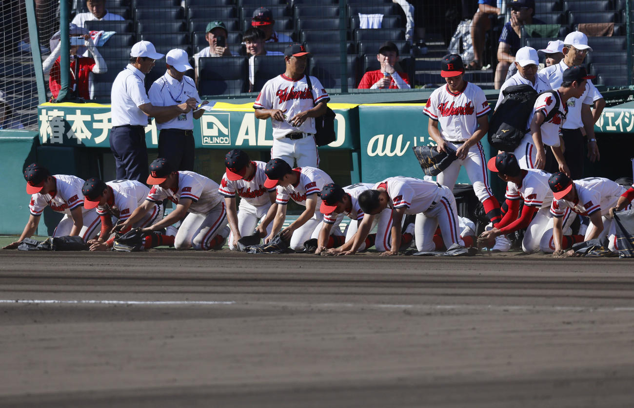 北陸対慶応　慶応に敗れ土を拾う北陸ナイン（撮影・藤尾明華）