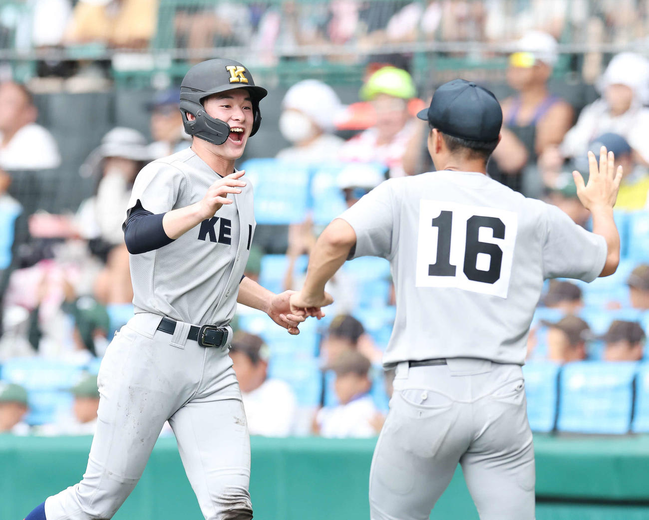 慶応対広陵　1回表慶応2死二、三塁、延末が先制左前2点適時打を放つ間に生還し、笑顔でタッチする丸田（撮影・宮地輝）
