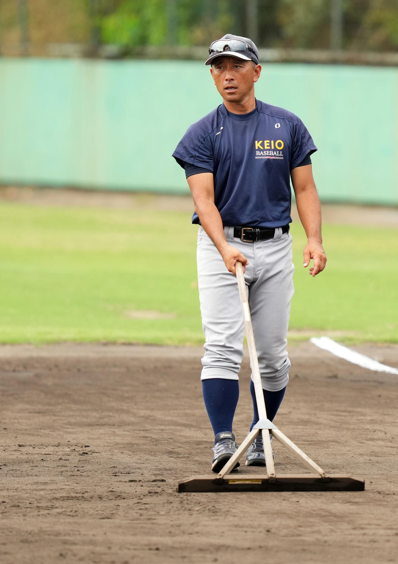 グラウンド整備をする慶応・森林監督（撮影・横山健太）