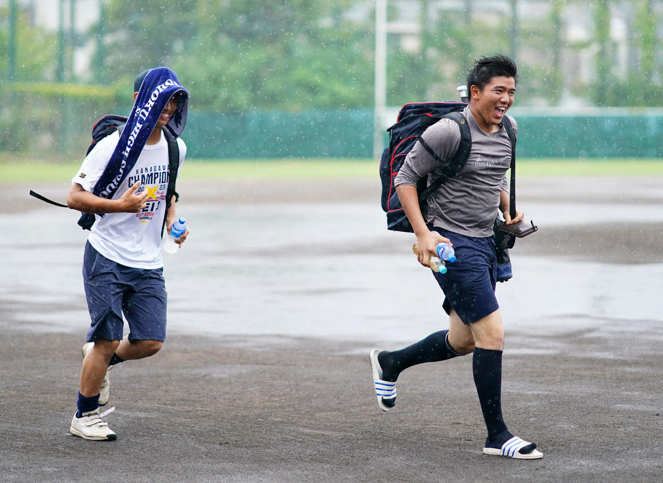 突然の雨で足早にグラウンドを後にする慶応・小宅（左）と足立（撮影・横山健太）