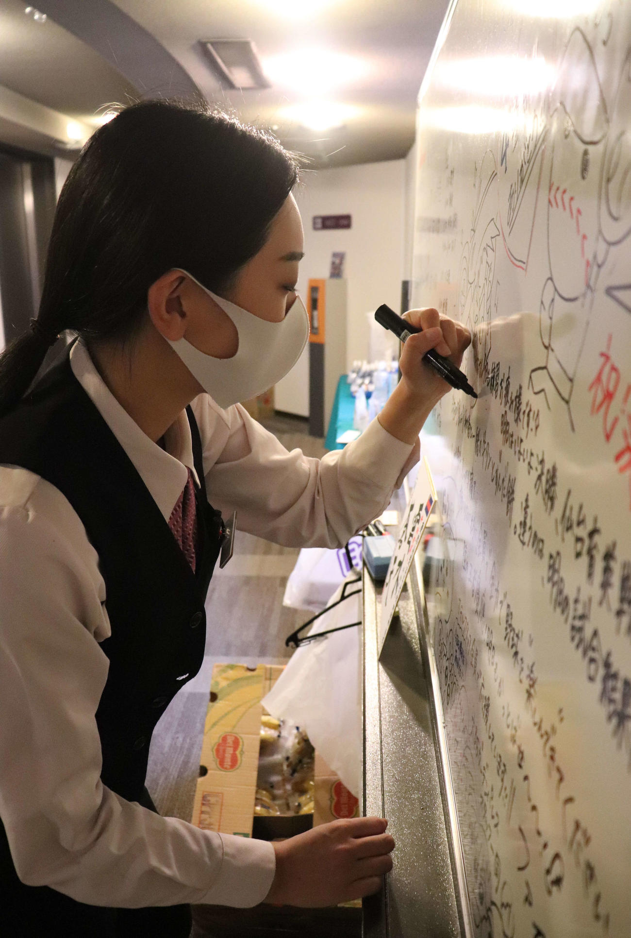 慶応ナインへ手書きのホワイトボードに思いをしたためる、宿舎スタッフの奥野花梨さん（撮影・中島麗）