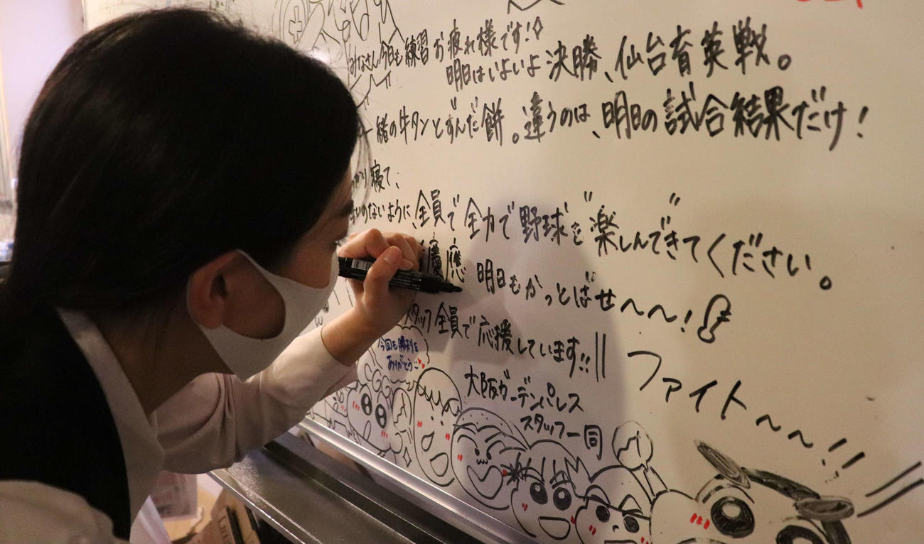 慶応ナインへ手書きのホワイトボードに思いをしたためる、宿舎スタッフの奥野花梨さん（撮影・中島麗）