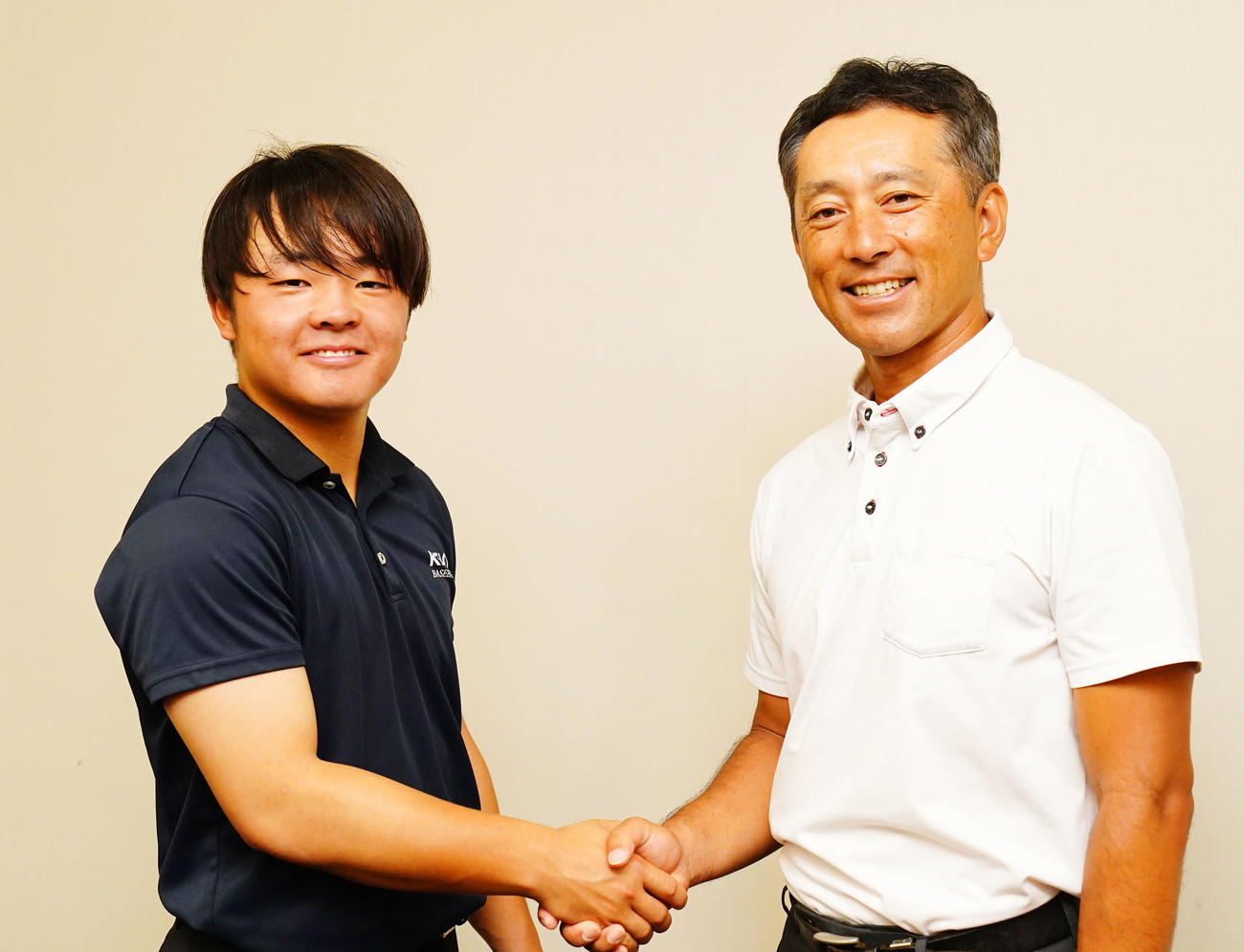 笑顔で握手を交わす慶応・大村主将（左）と森林監督（撮影・横山健太）