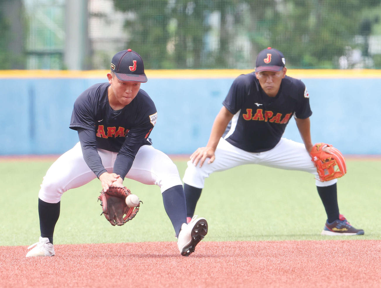 U12日本代表・井端監督（右）に見つめられながらノックを受けるU18日本代表・小林（撮影・宮地輝）