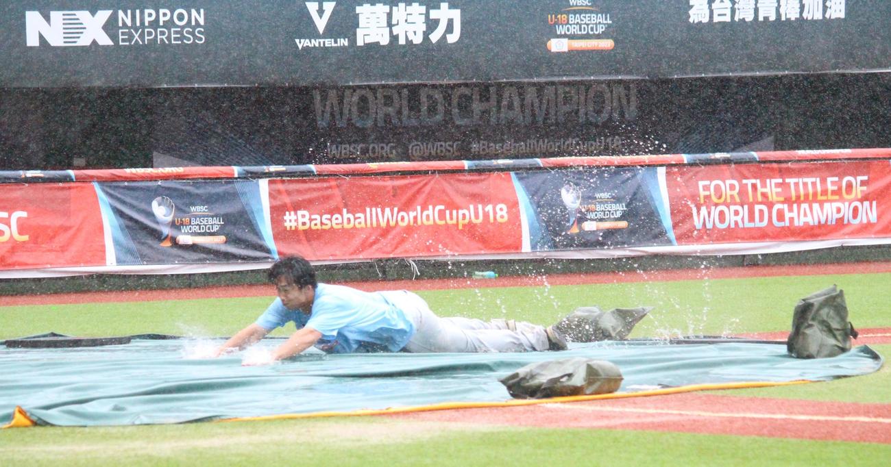 降雨のため試合開始が遅れる間に、ヘッドスライディングをして盛り上げる大会スタッフ（撮影・保坂恭子）