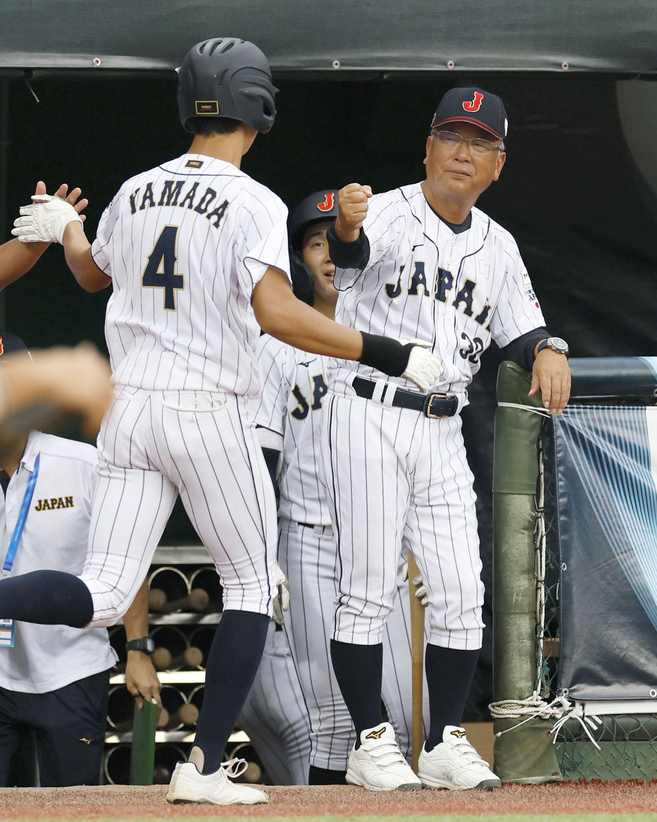 韓国戦の6回、本塁打の山田を迎える馬淵監督（右）＝台北（共同）