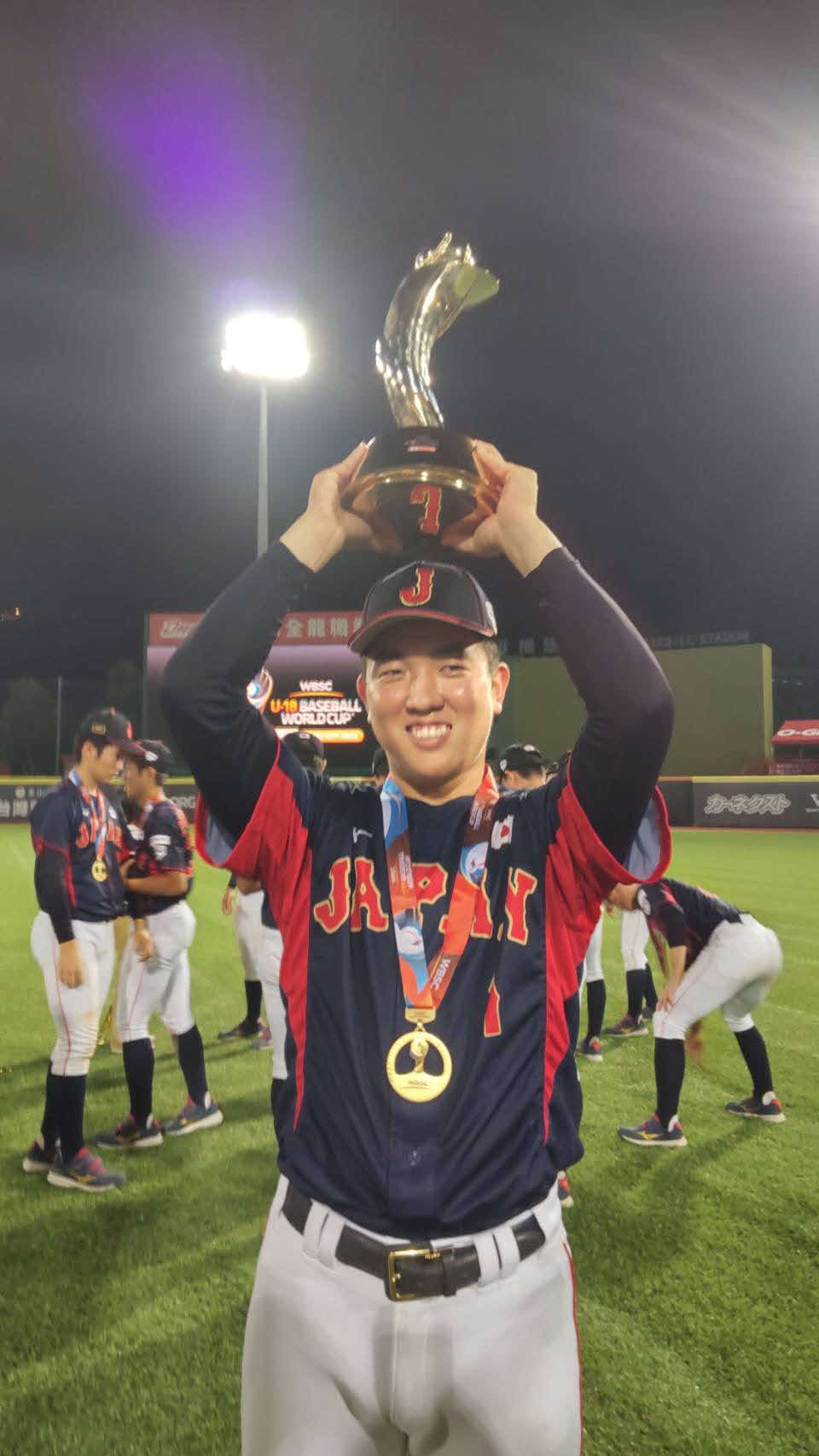 セレモニー後のグラウンドでU18日本代表の小林主将は笑顔で世界一のトロフィーを掲げた（撮影・柏原誠）