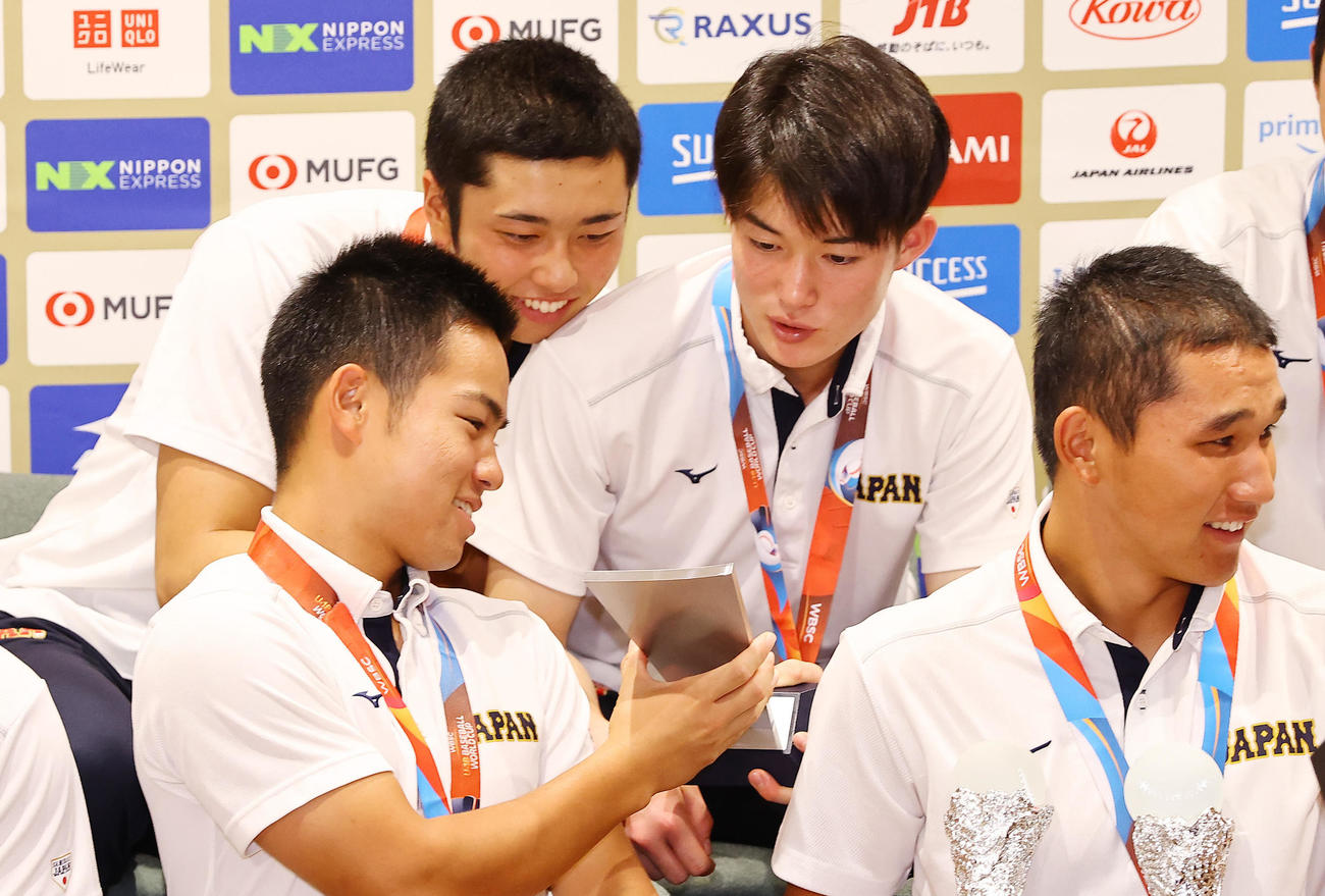 会見で緒方（左）のMVPトロフィーをまじまじと見つめる高橋（左から2人目）と丸田（同3人目）（撮影・垰建太）