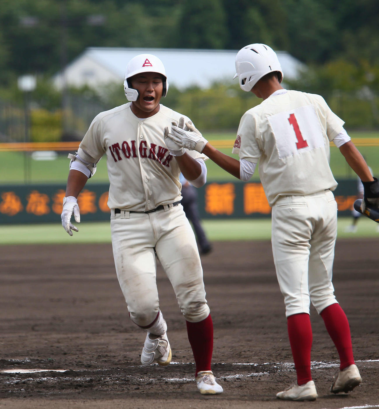 2回、先制本塁打を放ち出迎える糸魚川の次打者・山岸（1番）とタッチをかわす中沢