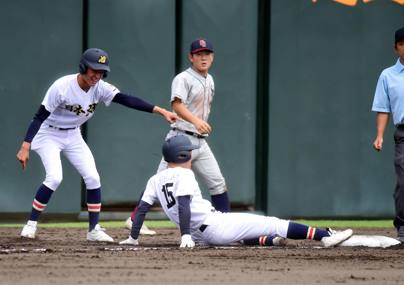 右中間へ走者一掃の三塁打を放った日本文理・小川は勢い余って三塁ベース上で転倒（右）