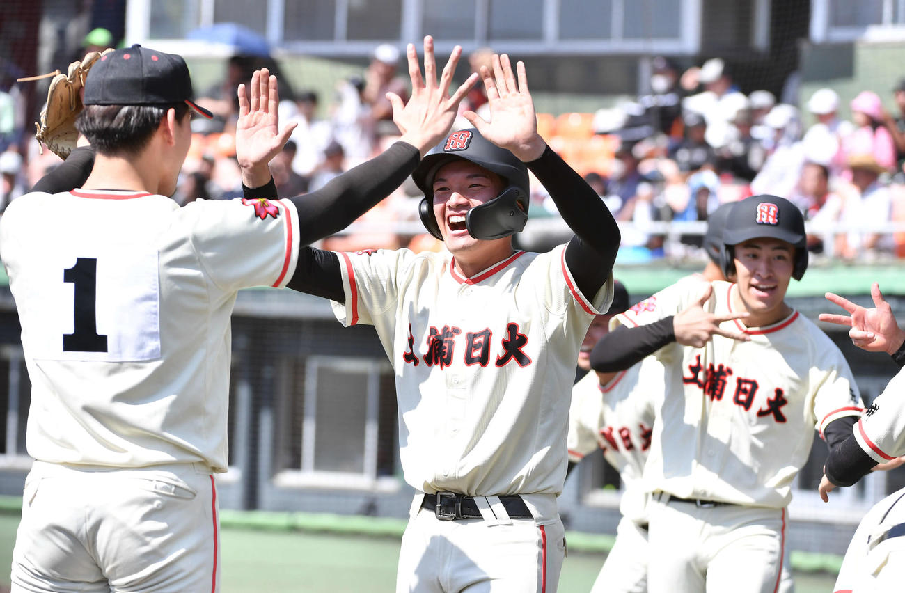 土浦日大対おかやま山陽　1回表土浦日大2死一、二塁、太刀川の先制2点適時中二塁打で生還し、藤本（左）と笑顔でタッチを交わす香取（撮影・岩下翔太）