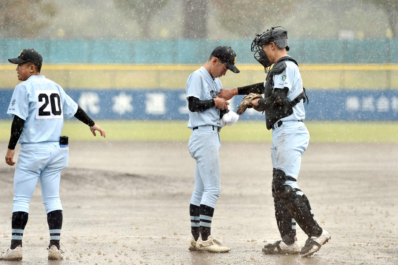 盛岡中央対学法石川　3回表盛岡中央2死一、三塁、濡れたボールを拭く学法石川・佐藤翼（中央）（撮影・相沢孔志）