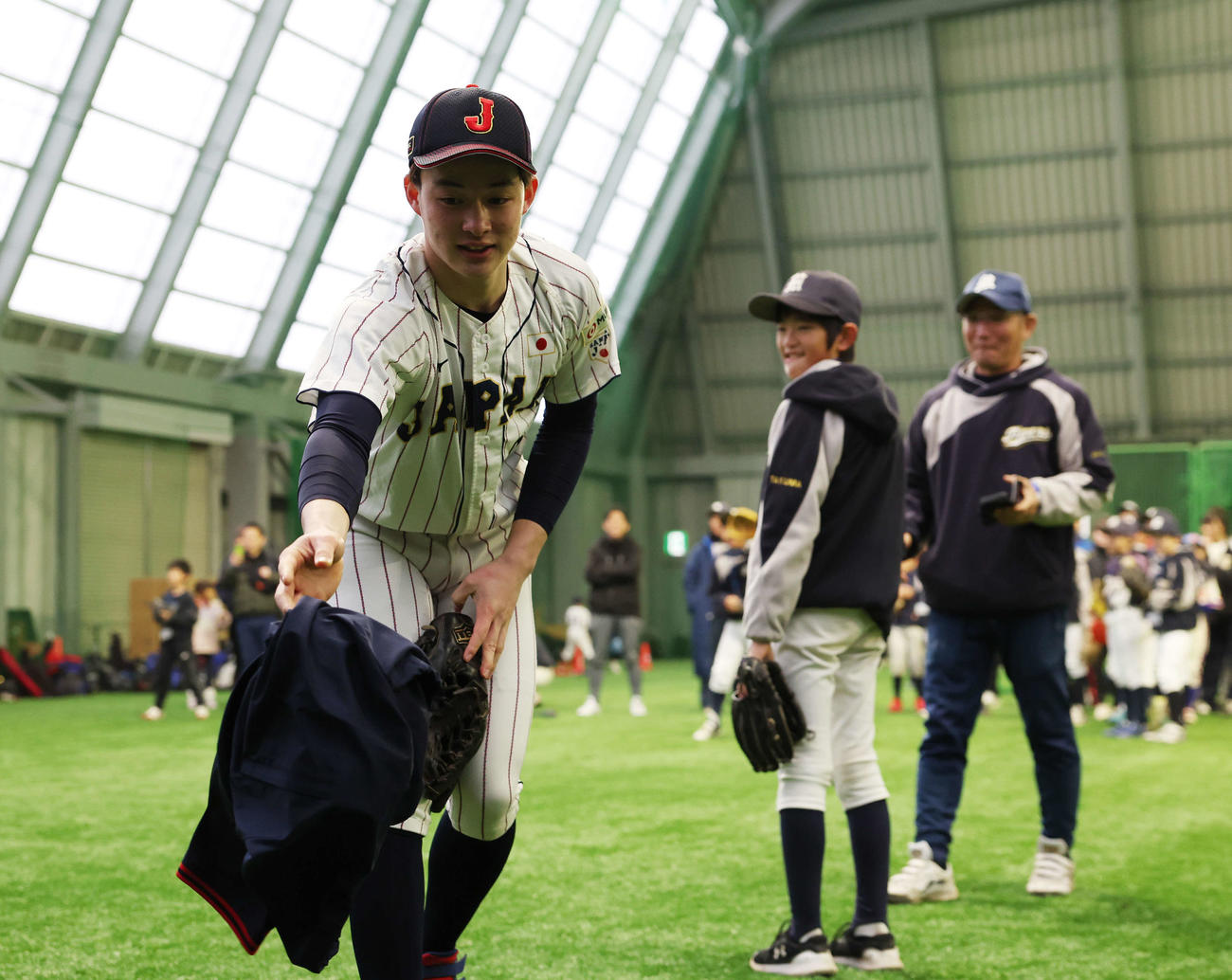 「野球で遊ぼう2024」で子どもたちとの記念撮影のため、上着を脱ぎ侍ジャパンU18のユニホーム姿になる慶応・丸田（撮影・宮地輝）