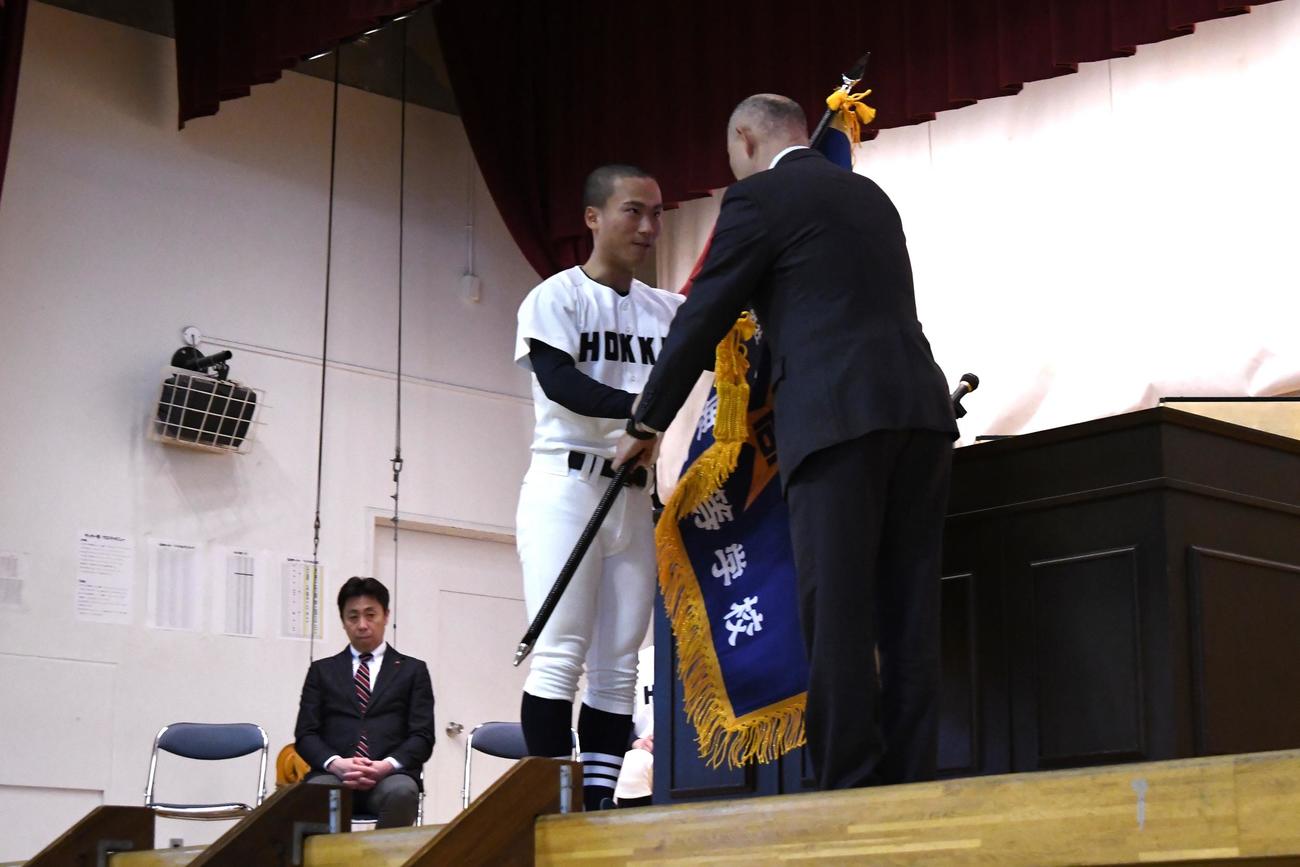 北海の秋山校長から選抜旗を手渡される金沢主将（左）（撮影・石井翔太）