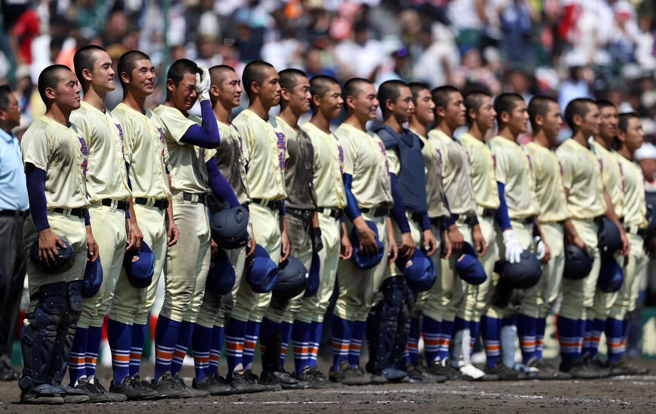 19年夏の甲子園3回戦、タイブレーク延長14回で智弁和歌山にサヨナラ勝ちし、校歌斉唱で1人涙をぬぐう星稜・奥川（左から4人目）