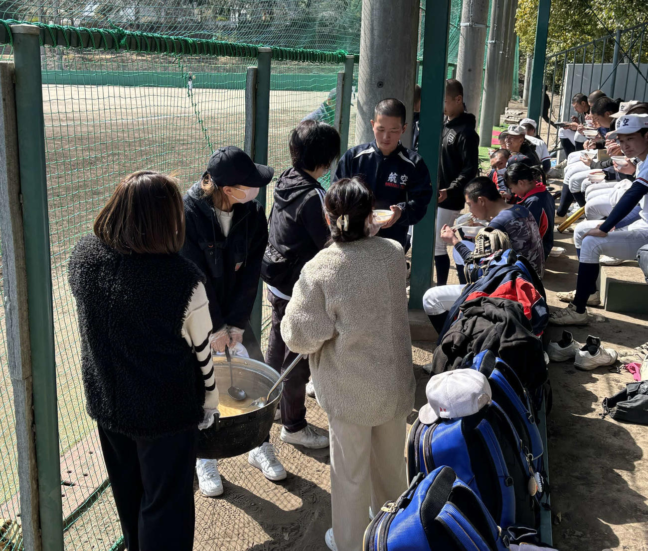 太成学院大高の部員の保護者らから炊き出しの豚汁を受け取る日本航空石川の選手たち（撮影・古財稜明）