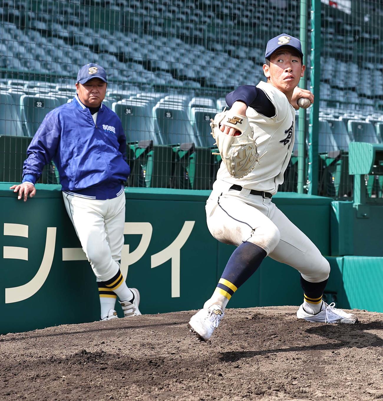 創志学園・門馬監督（左）のチェックを受けながらブルペンで投球練習をするエース山口（撮影・上田博志）
