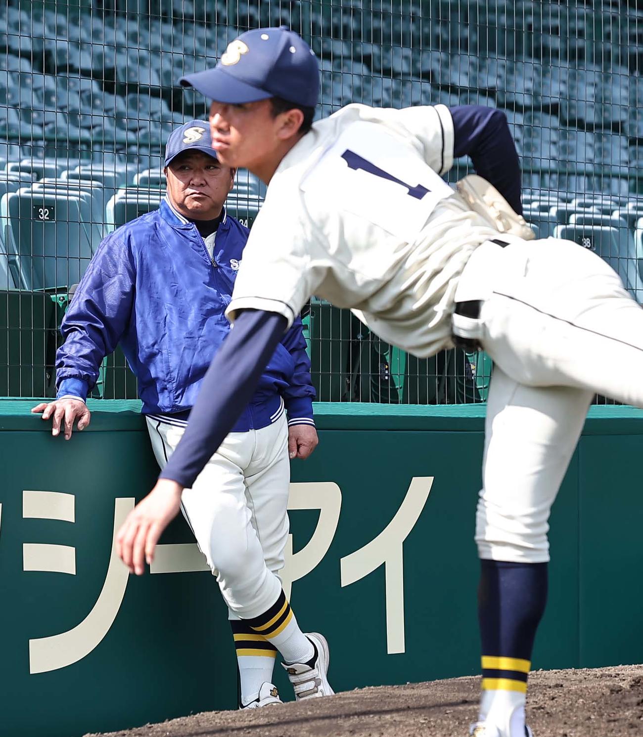 創志学園・門馬監督（左）はエース山口の投球練習を見守る（撮影・上田博志）