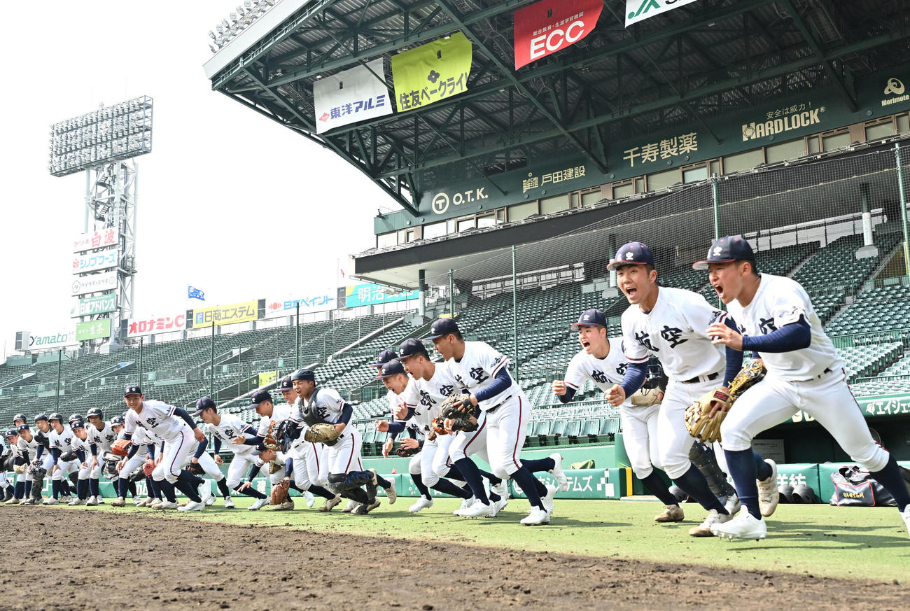 甲子園球場のグラウンドに元気よく飛び出す宝田主将（右端）ら日本航空石川ナイン（撮影・石井愛子）