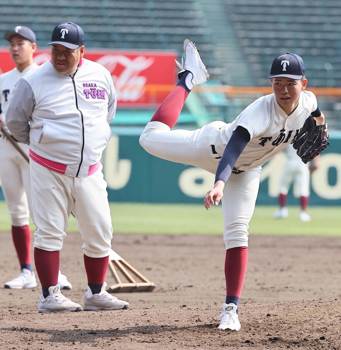 大阪桐蔭・西谷監督（左）のチェックを受けながら投球練習をする森（撮影・上田博志）