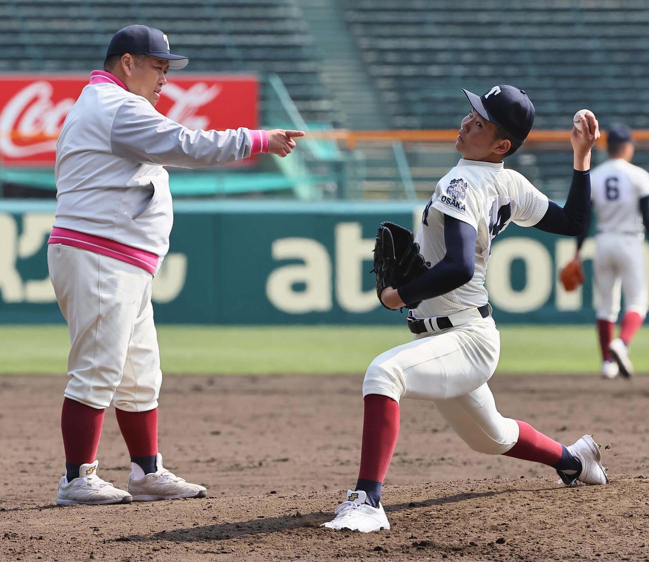 大阪桐蔭・西谷監督（左）のチェックを受けながら投球練習をする森（撮影・上田博志）