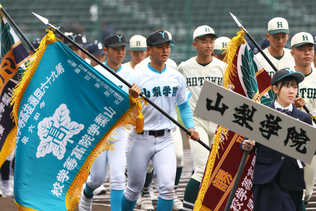 開会式のリハーサルを終えグラウンドを移動する山梨学院の中原主将（左から2人目）。右端は報徳学園の間木主将（撮影・上山淳一）