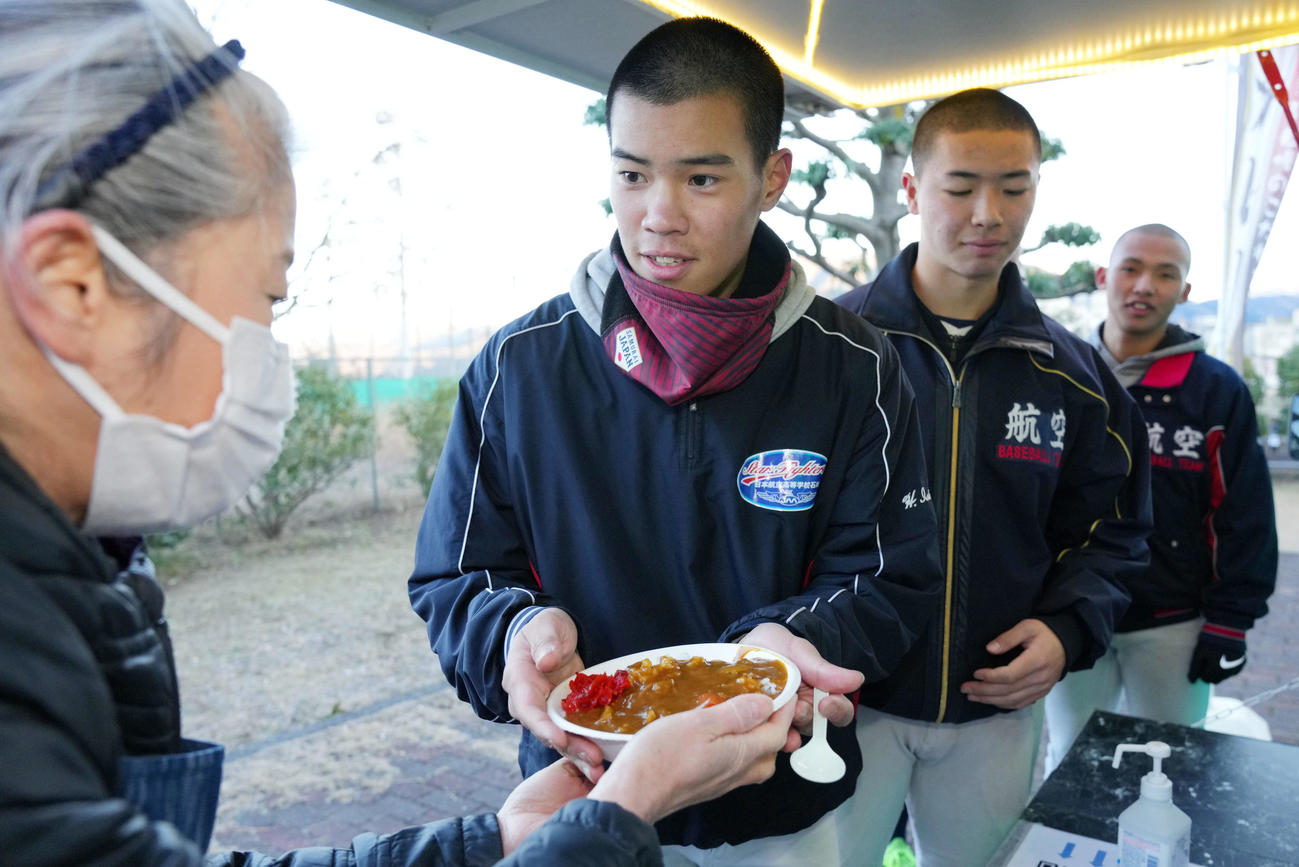 練習後に地元ボランティアの人たちからカレーを受け取る日本航空石川の選手たち