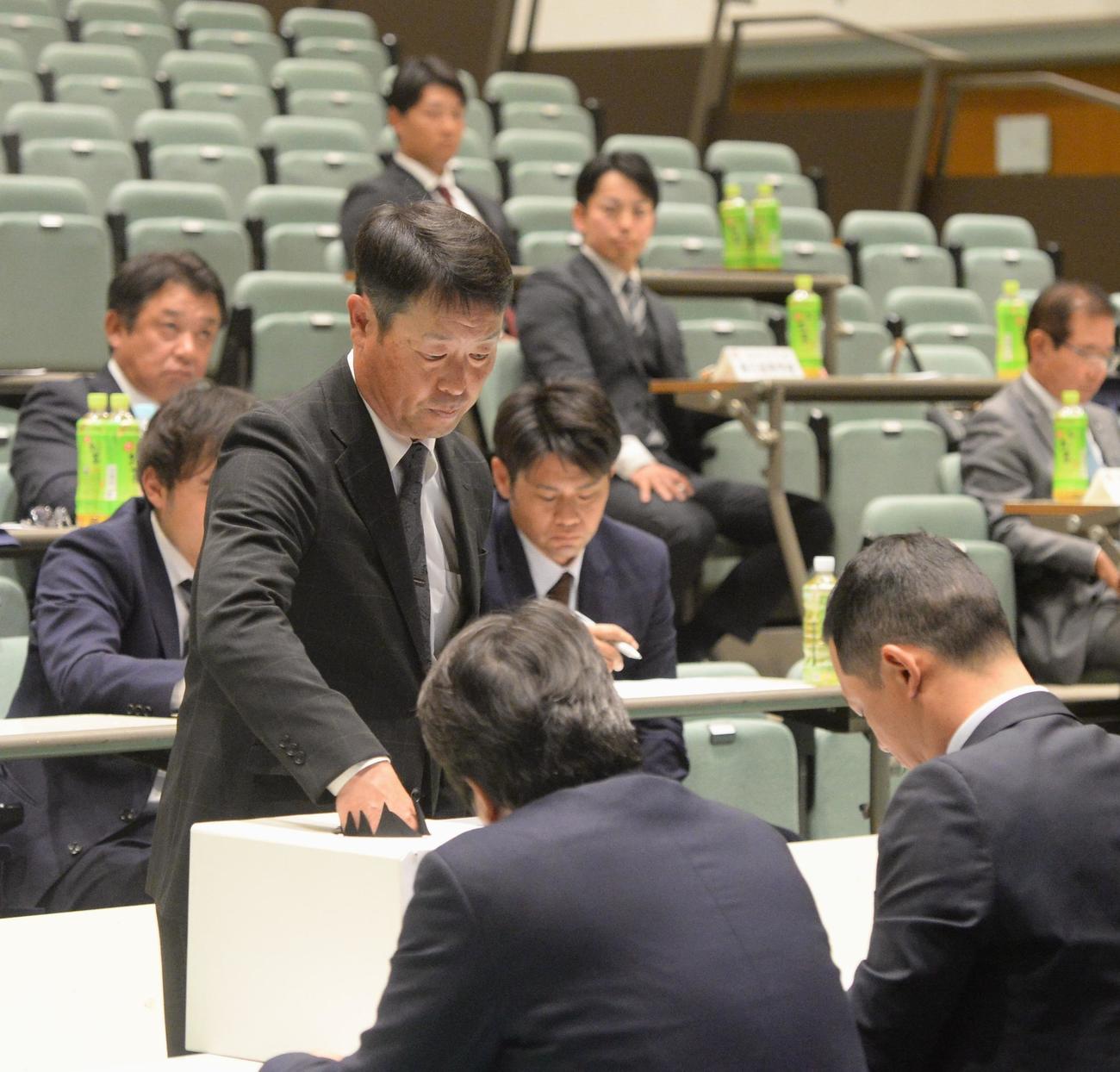 抽選会に出席し、くじを引く春日・八塚監督（中央）（撮影・佐藤究）