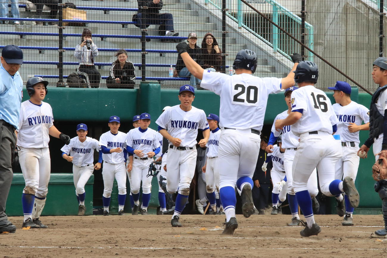 両手を挙げてベンチへ向かう米田（背番号20）を迎える札幌龍谷学園ナイン（撮影・保坂果那）