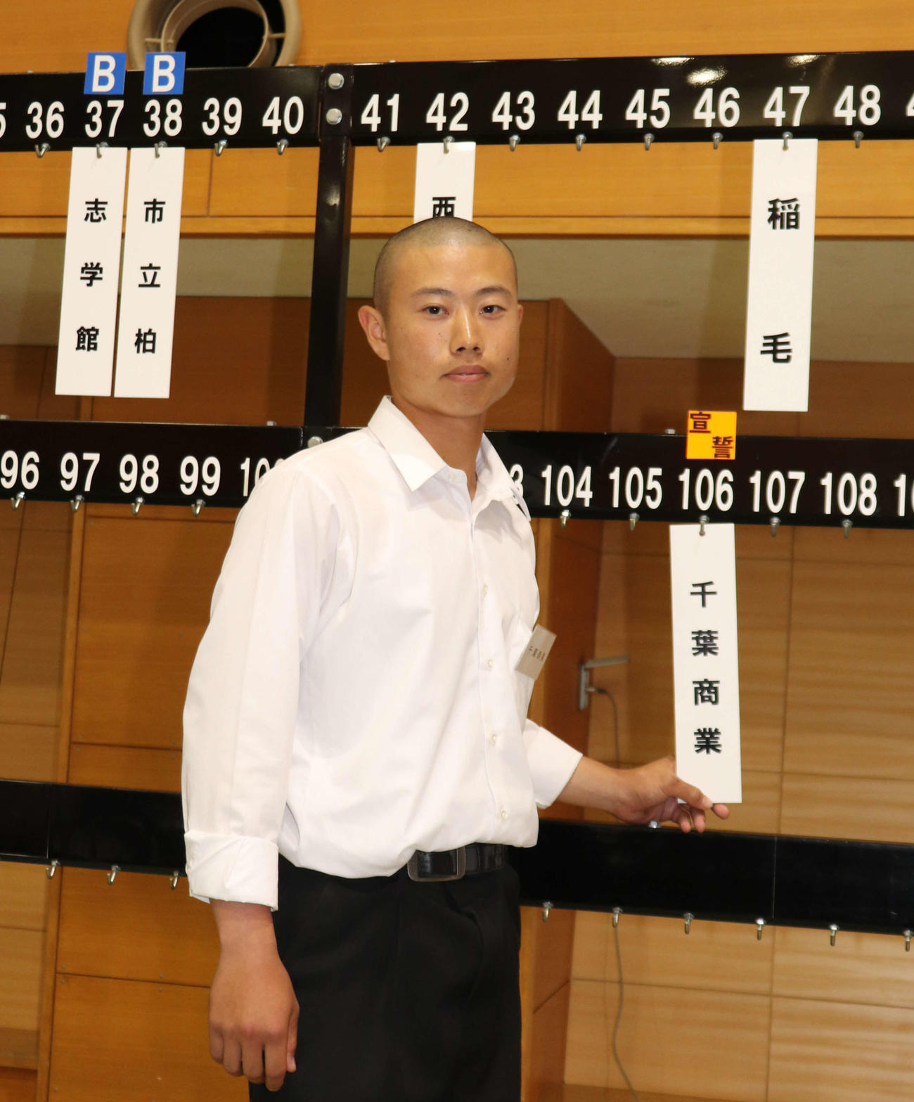 106回大会にちなみ、106番の選手宣誓の番号を引いた千葉商の麻生陸斗主将が学校名の札を前に緊張した表情を浮かべる（撮影・保坂淑子）