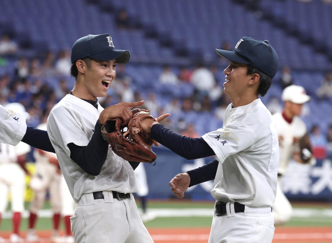 交野対枚方津田　3回表の交野の攻撃を終え2番手投手の大槙（左）は笑顔で先発から右翼に回った敷田とタッチを交わす（撮影・白石智彦）